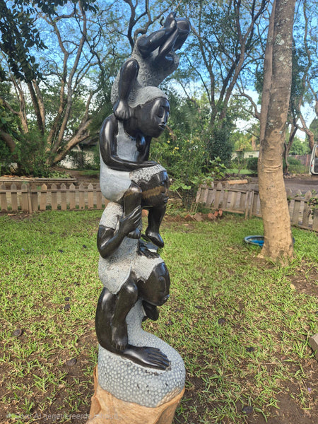 hoog tuinbeeld in steen, 4 kinderen in elkaars schouders