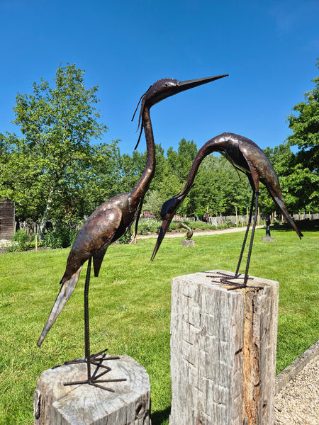 koppel reigers in metaal, voorovergebogen reiger, en rechtopstaande reiger, gemaakt van olievaten